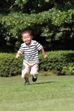 Japon çocuk (3 yaşında çimenlerin üzerinde çalışan)