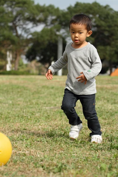 日本男孩踢一个黄色的球 (3 岁) — 图库照片