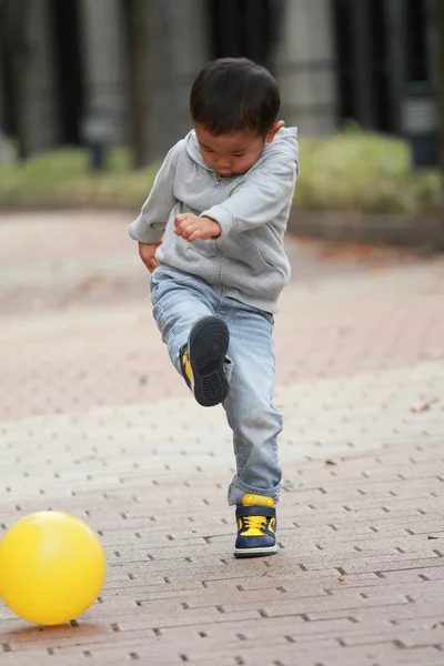 Japonês menino chutando uma bola amarela (3 anos de idade ) — Fotografia de Stock