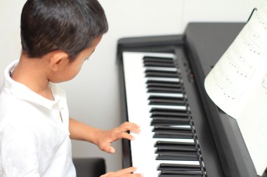 Japanese boy playing a piano (5 years old) clipart