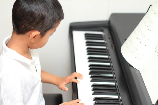 Japanese boy playing a piano (5 years old) — Stock Photo, Image