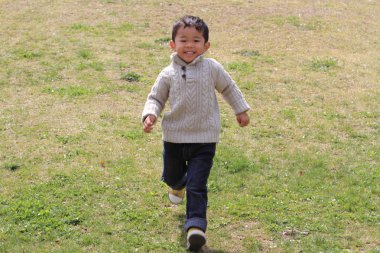 Japon çocuk (3 yaşında çimenlerin üzerinde çalışan)