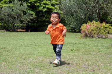 Japon çocuk (1 yaşında çimenlerin üzerinde çalışan)