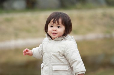 Japanese girl taking a walk in the park (1 year old) clipart
