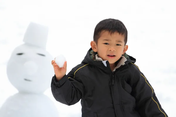 雪合戦と雪だるま (4 歳児を持つ日本男児) — ストック写真