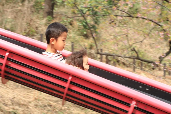 Japanese brother and sister on the slide (6 years old boy and 1 year old girl) — Stock Photo, Image