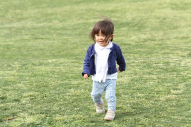 Japanese girl walking on the grass (1 year old) clipart