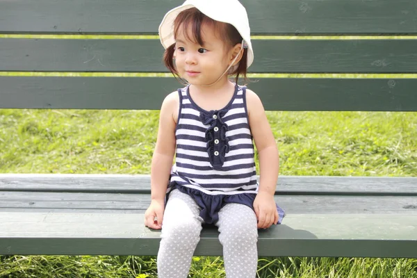 Japanese girl sitting on the bench in the field (1 year old) — Stock Photo, Image