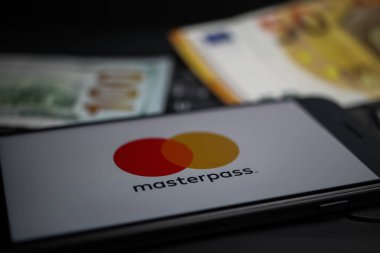 Viersen, Almanya - 9 Nisan. 2020: Cep telefonu ekranının kapatılması ve bilgisayar klavyesindeki ana kart ödeme sağlayıcısının logosu bize dolar para geçmişini bulanıklaştırdı