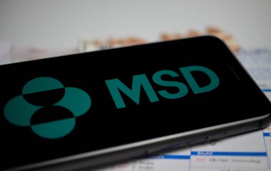 Viersen, Almanya - 9 Nisan. 2020: Cep telefonu ekranının MSD Sharp ve Dohme ilaç şirketlerinin logosu, bulanık haplar ve laboratuvar geçmişi ile kapatılması