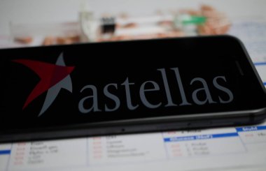 Viersen, Almanya - 9 Nisan. 2020: Cep telefonu ekranını astellas ilaç şirketinin logosu, bulanık haplar ve laboratuvar geçmişi ile kapat