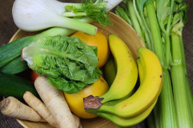 Sağlıklı çiğ kış yemeklerinin olduğu kaseye bakın: kereviz çubukları, muz, rezene ve maydanoz kökleri, salata, greyfurtlar