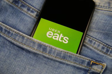 Viersen, Almanya - 9 Kasım. 2020: Yemek dağıtım sağlayıcısı ile izole edilmiş cep telefonunu kapat Uber kot pantolon cebinde logo yiyor