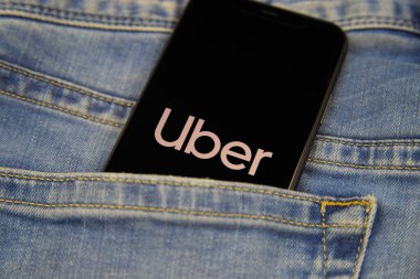 Viersen, Almanya - 9 Mayıs. 2020: Yolcu taşıma şirketi Uber logosu olan izole edilmiş cep telefonunun kot cebinde kapatılması