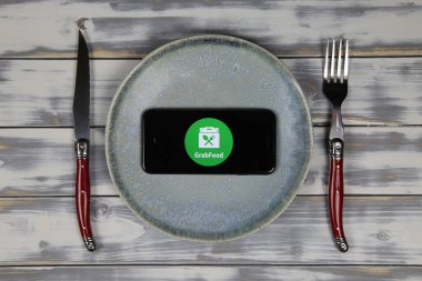 Viersen, Almanya - 9 Mayıs. 2020: Tabak ve çatal bıçaklı ahşap masadaki yemek servisinin logosu ile cep telefonu ekranını kapat (merkeze odaklan)