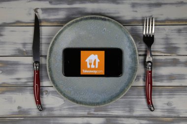 Viersen, Almanya - 9 Mayıs. 2020: Tabak ve çatal bıçak ile ahşap masa üzerinde yemek dağıtım hizmeti logosu içeren cep telefonu ekranını kapat (merkeze odaklan)