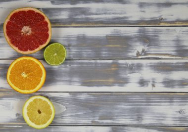 Arka arkaya dört izole edilmiş meyve parçasının yukarıdan görünüşü, kırmızı olgun greyfurt, turuncu, sarı limon ve yeşil kireç beyaz doğal ahşap masa üzerinde metin için yeri olan (meyvelere odaklan))