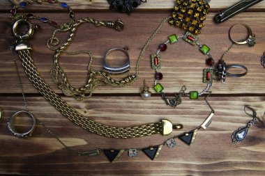 Ahşap masadaki izole edilmiş altın ve gümüş mücevher parçalarının yukarıdan görünüşü