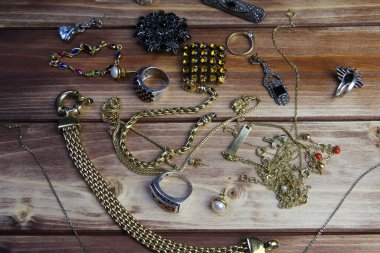 Ahşap masadaki izole edilmiş altın ve gümüş mücevher parçalarının yukarıdan görünüşü