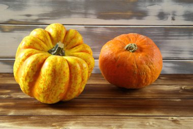 İki izole edilmiş parlak turuncu olgun balkabağına yakın beyaz ve kahverengi ahşap ahşap arka planda