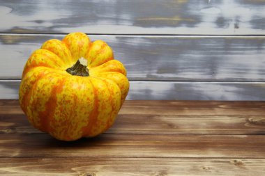 İzole edilmiş parlak sarı turuncu olgun balkabağına yakın beyaz ve kahverengi ahşap ahşap kaplama arka plan