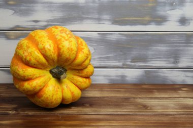 İzole edilmiş parlak sarı turuncu olgun balkabağına yakın beyaz ve kahverengi ahşap ahşap kaplama arka plan