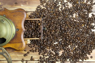 Eski, izole edilmiş eski el kitabında tepeden tırnağa kahverengi ahşap masa üzerinde çiğ fasulye yığınıyla klasik kahve öğütücüsü.