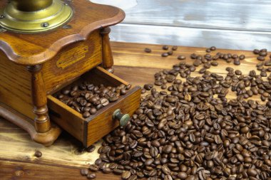 Eski, izole, ahşap ahşap kahve öğütücüsü çekmecesini kapatıyorum. Kahverengi ahşap masa üzerinde çiğ fasulye yığını var.