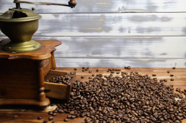 Eski, izole, ahşap ahşap kahve öğütücüsü çekmecesini kapatıyorum. Kahverengi ahşap masa üzerinde çiğ fasulye yığını var.