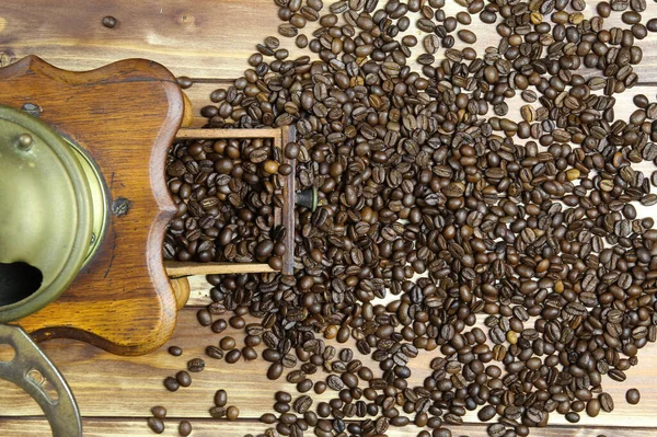 Eski, izole edilmiş eski el kitabında tepeden tırnağa kahverengi ahşap masa üzerinde çiğ fasulye yığınıyla klasik kahve öğütücüsü.