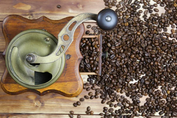 Eski, izole edilmiş eski el kitabında tepeden tırnağa kahverengi ahşap masa üzerinde çiğ fasulye yığınıyla klasik kahve öğütücüsü.