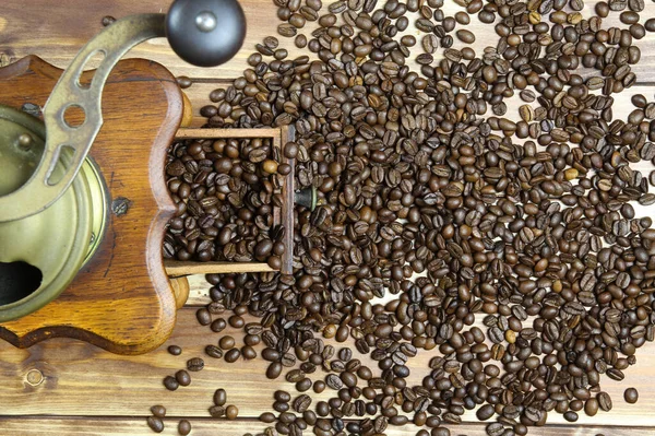 Eski, izole edilmiş eski el kitabında tepeden tırnağa kahverengi ahşap masa üzerinde çiğ fasulye yığınıyla klasik kahve öğütücüsü.