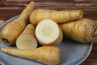 Mavi porselen tabakta çiğ, izole edilmiş havuç kökü sebzelerini kapatın.