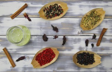 Cin tonik, kırmızı biber, kurutulmuş amber çiçekleri, tarçın çubukları, ardıç üzümleri, kakule doğal botanik malzemeleriyle beyaz kereste masasının tepesinde.