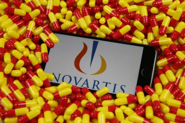 Viersen, Almanya - 9 Nisan. 2020: Cep telefonu ekranının üzerinde Novartis ilaç şirketinin logosu olan kırmızı ilaç kapsüllerini kapayın (logonun merkezine odaklanın)