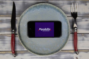 Viersen, Almanya - 9 Mayıs. 2020: Tabak ve ahşap masadaki cep telefonunun kapatılması, Mondelez gıda şirketinin logo harfli çatal bıçak takımı (merkeze odaklan)