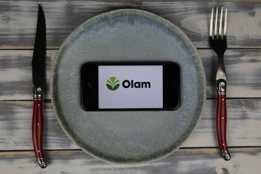 Viersen, Almanya - 9 Mayıs. 2020: Tabak ve ahşap masadaki cep telefonunun kapatılması, olam gıda şirketinin logosu olan çatal bıçak takımı (merkeze odaklan)