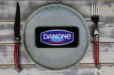 Viersen, Almanya - 9 Mayıs. 2020: Tabak ve ahşap masadaki cep telefonunun kapatılması, danone gıda şirketinin logo harfli çatal bıçak takımı (merkeze odaklan)