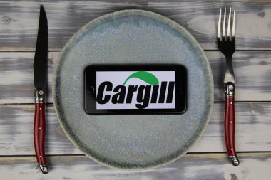 Viersen, Almanya - 9 Mayıs. 2020: Tabak ve ahşap masadaki cep telefonunun kapatılması, kargill gıda şirketinin logosu olan çatal bıçak takımı (merkeze odaklan)