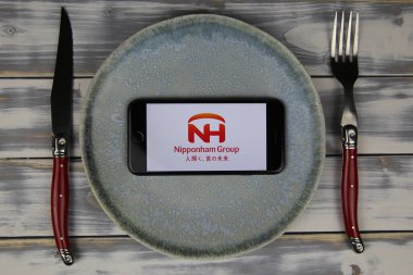 Viersen, Almanya - 9 Mayıs. 2020: Tabak ve ahşap masadaki cep telefonunun kapatılması, Japon Nipponham Grup Gıda Şirketi 'nin logo harfli çatal bıçak takımı (merkeze odaklan)