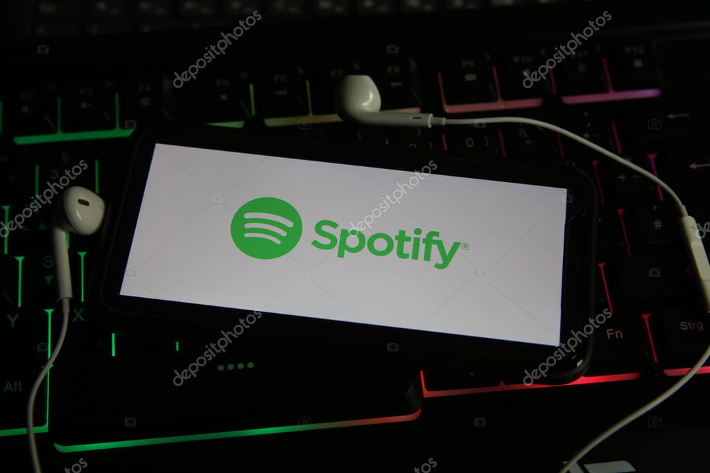 Viersen, Germany - January 9. 2021: Closeup of smartphone screen with logo lettering online music streaming service spotify on computer keyboard