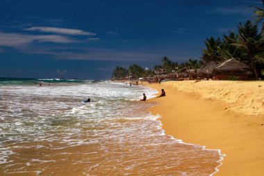Hikkaduwa, Sri Lanka - 9 Aralık. 2010: Tropikal sahilde palmiye ağaçları ve dalgalı deniz manzarası