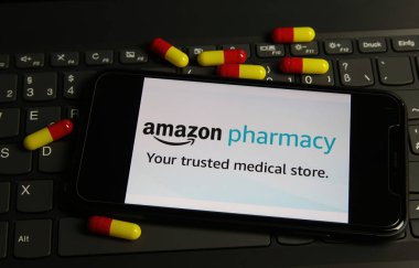 Viersen, Almanya - 9 Şubat. 2021: Bilgisayar klavyesinde Amazon eczane hap paketinin logosu olan akıllı telefon ekranının kapatılması