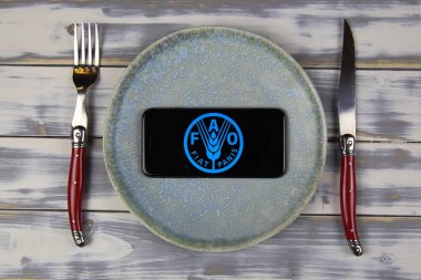 Viersen, Germany - February 9. 2021: Closeup of smartphone screen with logo lettering of FAO food and agriculture organziation on plate with cutlery clipart