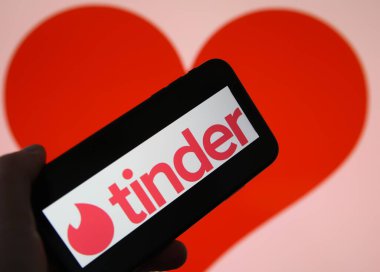 Viersen, Almanya - 9 Şubat. 2021: Cep telefonu ekranının çevrimiçi randevu ajansı uygulaması Tinder 'ın logosu ve bulanık kalp geçmişi ile kapatılması