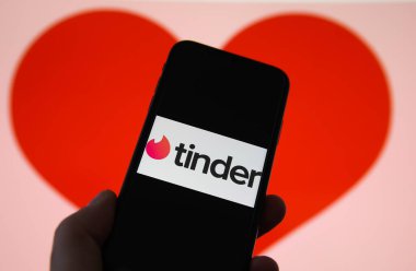 Viersen, Almanya - 9 Şubat. 2021: Cep telefonu ekranının çevrimiçi randevu ajansı uygulaması Tinder 'ın logosu ve bulanık kalp geçmişi ile kapatılması