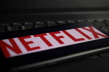 Viersen, Almanya - 1 Mart. 2021: Bilgisayar klavyesindeki çevrimiçi yayın hizmeti netflix 'inin logo harfleriyle akıllı telefon ekranının kapatılması