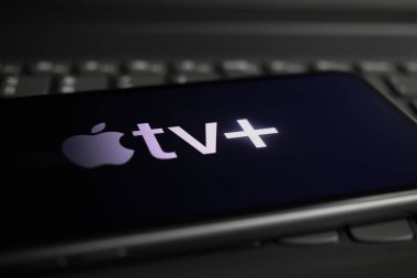 Viersen, Almanya - 1 Mart. 2021: Bilgisayar klavyesinde online yayın yapan elma TV 'nin logo harfleriyle akıllı telefon ekranının kapatılması