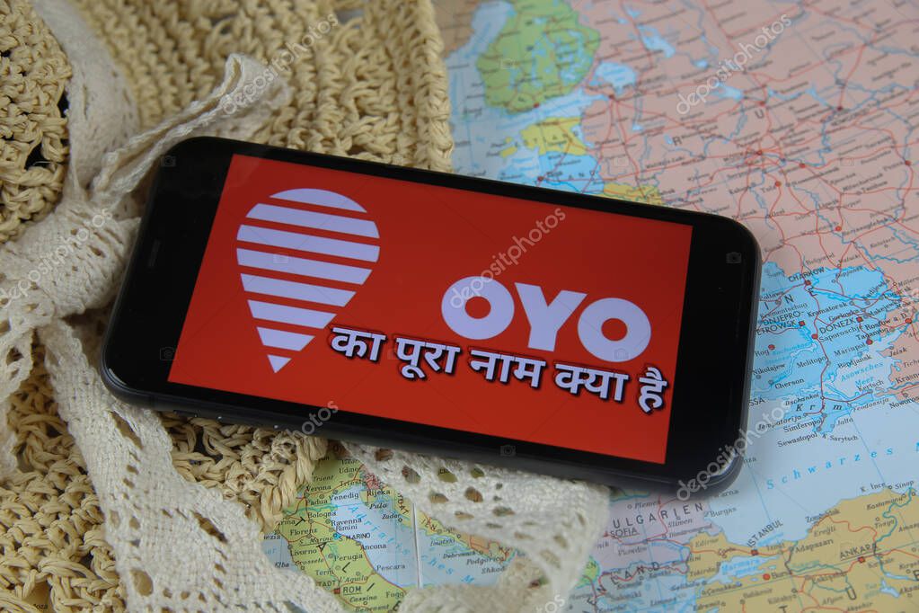 Viersen, Germany - March 1. 2021: Closeup of mobile phone screen with logo lettering of oyo online travel agency on map with sun hat