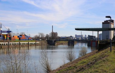 Krefeld (Uerdingen) - 1 Mart. 2021: Mavi gökyüzüne karşı vinç, su yolu teknesi ve fabrika binasıyla nehir ren kıyısındaki eski iç kesimlere bakın.